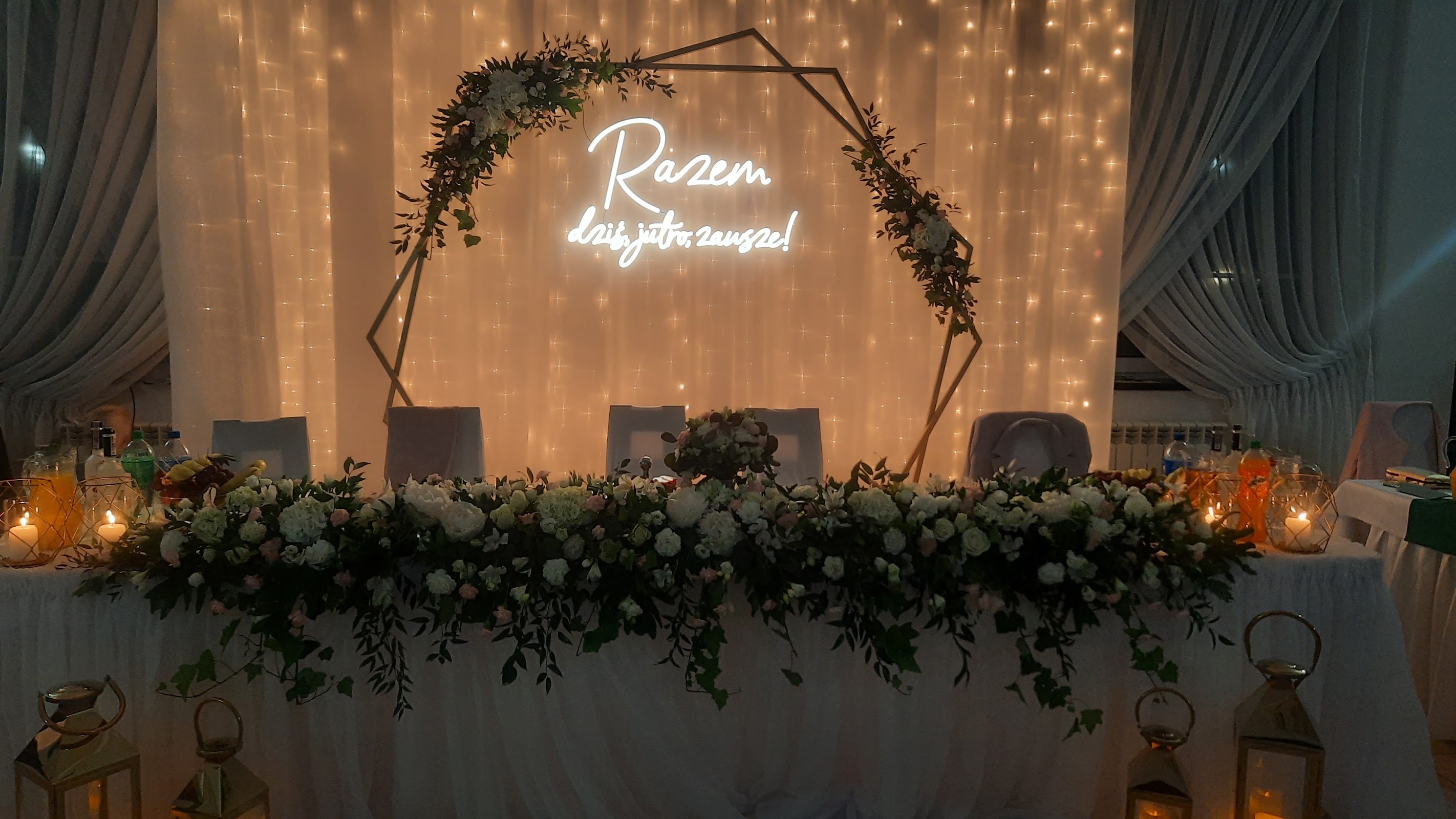Stół pary młodej w sali Zajazdu Paryż, kwiaty, świece i neon z napisem Razem